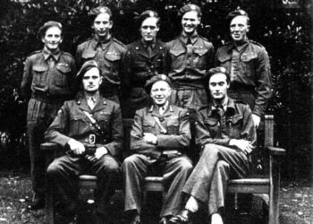 Surrounding their boss Leif Tronstad (front row, center) are most of the Vemork saboteurs, including (front row left to right) Jens Anton Poulsson and Joachim Ronneberg, and (back row left to right) Hans Storhaug, Fredrik Kayser, Kasper Idland, Claus Helberg, and Birger Stromsheim.